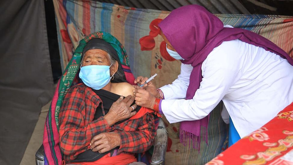 Nepal: Eine ältere Frau wird gegen Corona geimpft. 