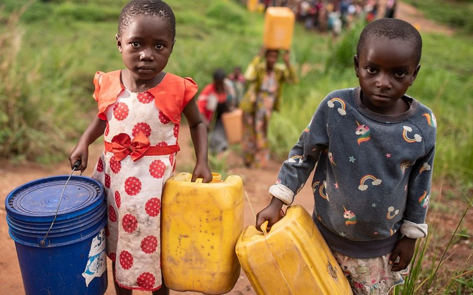 Weltwassertag 2021: Zwei Kinder in der Demokratischen Republik Kongo tragen Behälter zum Wasserholen.