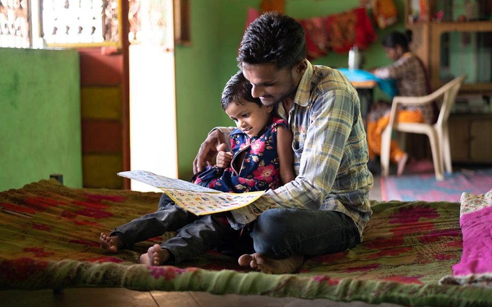 Ein Vater liest seinem Kind aus einem Buch vor.