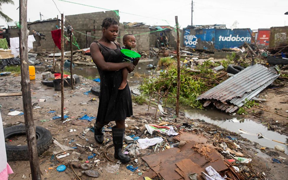 Zyklon Idai: Eine Frau mit einem Baby auf dem Arm geht durch Trümmer