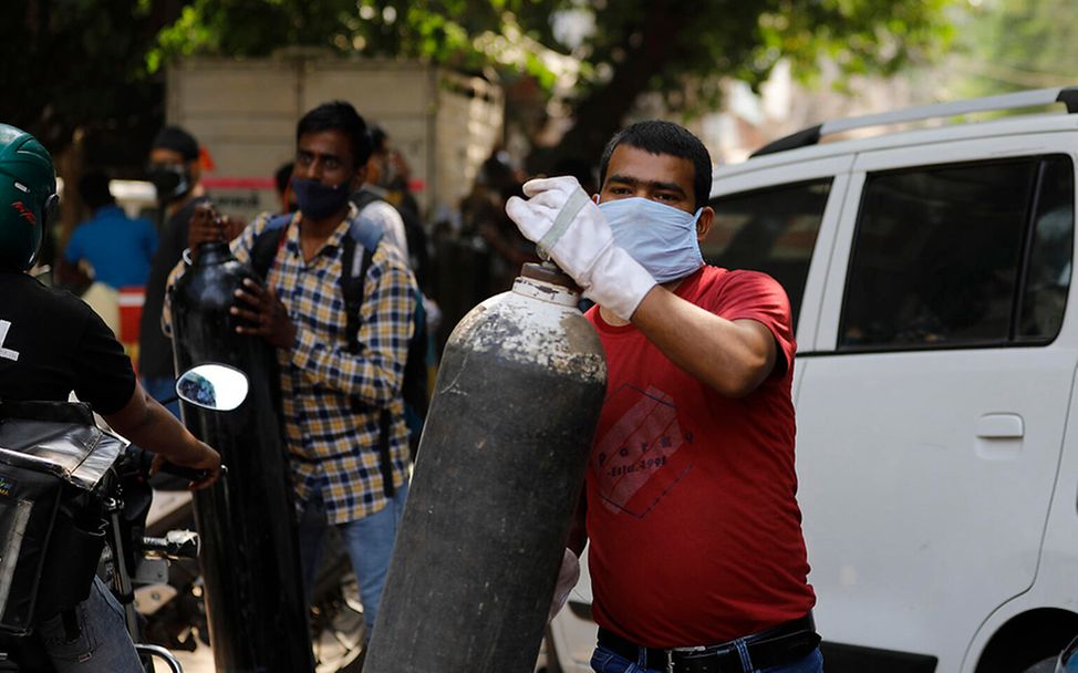 Corona Indien: Ein Mann trägt einen Behälter für Sauerstoff
