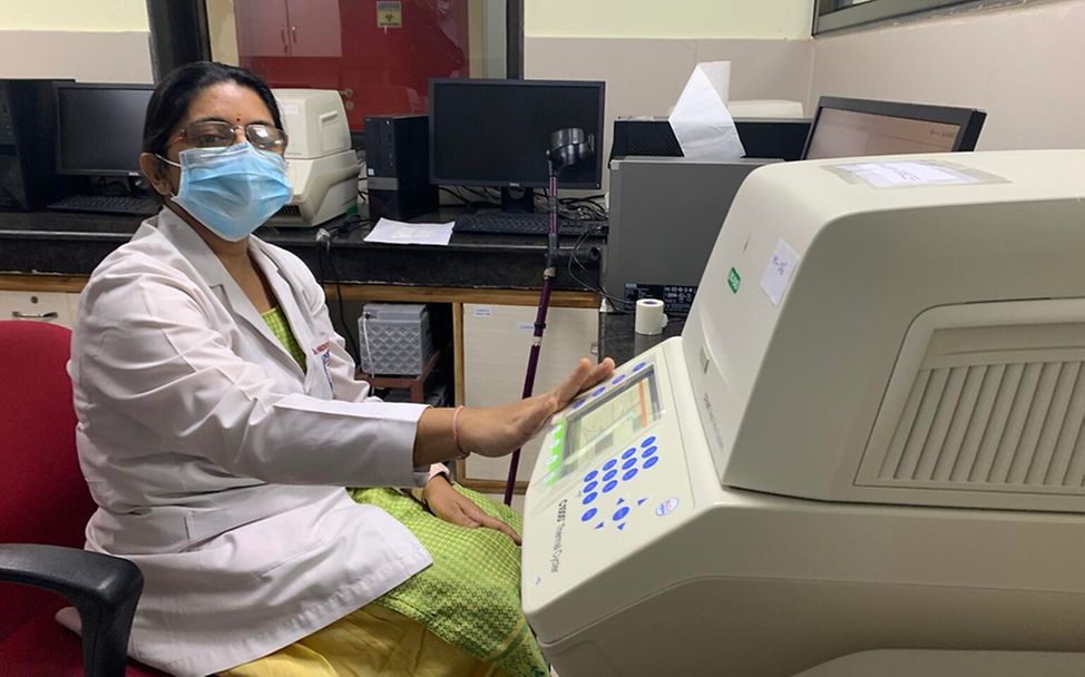 Corona in Indien: Eine Mitarbeiterin des Virologie-Labors zeigt die Maschine zur Auswertung von PCR-Tests