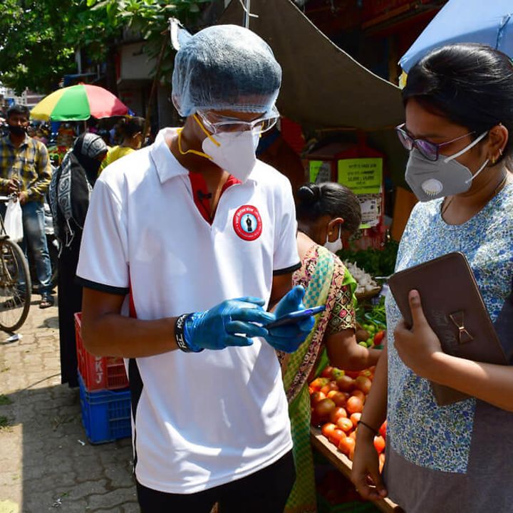 Corona in Indien: Ein Helfer klärt Menschen auf einem Marktplatz auf