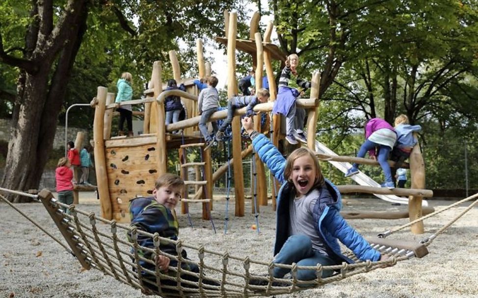 Eine Gruppe von Kindern spielt auf einem Spielplatz am Klettergerüst.
