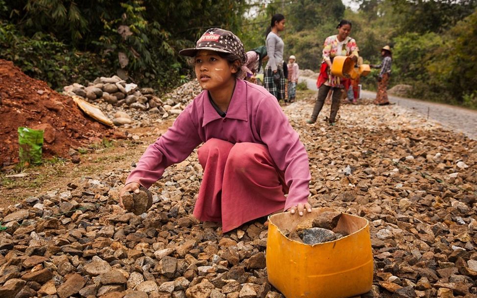 Lieferkettengesetz: In Myanmar sammelt ein Mädchen Steine für den Straßenbau auf.