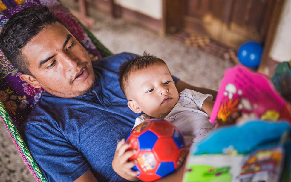 Guatemala: Vater liest seinem Sohn etwas vor.