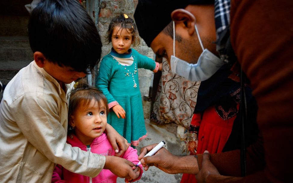 Subhan, ein Impf-Helfer, markiert den Finger eines kleinen Mädchens, das gerade geimpft wurde.
