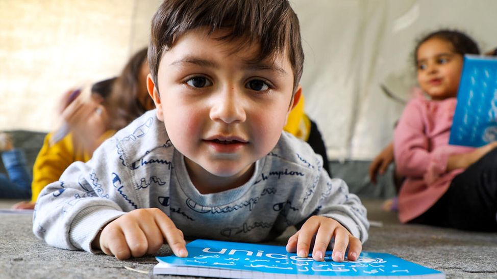 Afghanistan: Ahmad, 4, blättert in einem Zelt von UNICEF in einem Heft