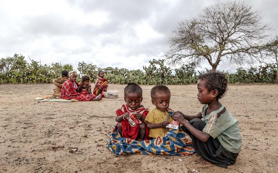 Hunger in Madagaskar: Kinder sitzen auf dem Boden und essen Erdnusspaste