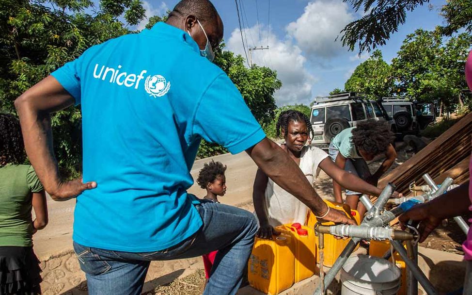Haiti Erdbeben Nothilfe: Ein UNICEF-Mitarbeiter hilft beim Befüllen von Wasserkanistern.