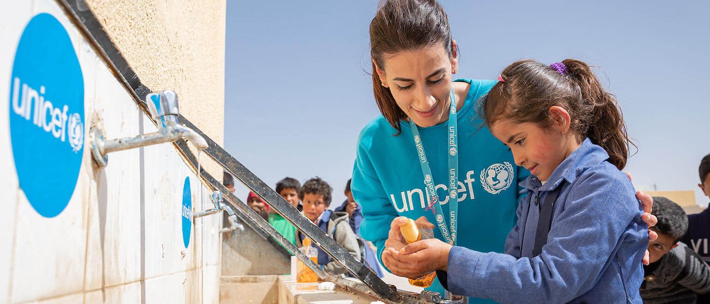 Kampf gegen das Coronavirus: UNICEF-Helferin zeigt Mädchen das richtige Händewaschen