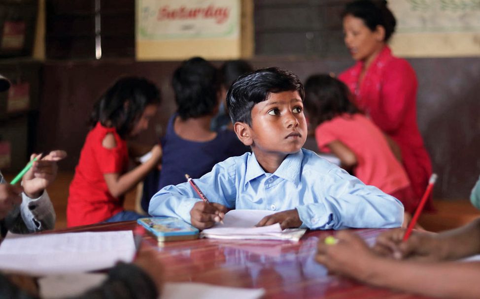Bildung in Nepal: Ein Junge schreibt etwas in sein Schulheft. 
