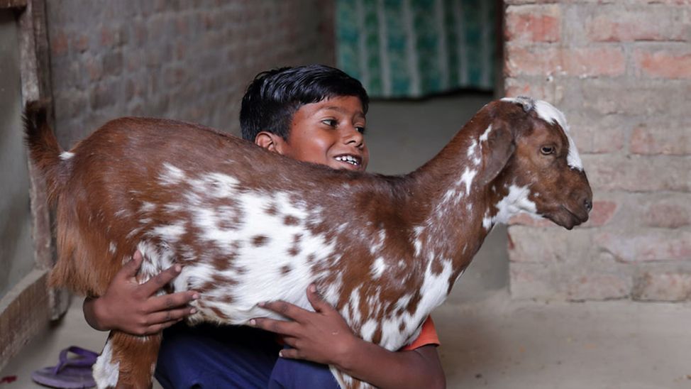 Bargeldhilfe (cash transfer) in Nepal: Ein Junge mit einer selbst gekauften Ziege im Arm. 