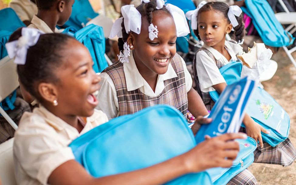 Spenden Haiti: Kinder packen UNICEF-Schulmaterial aus. 