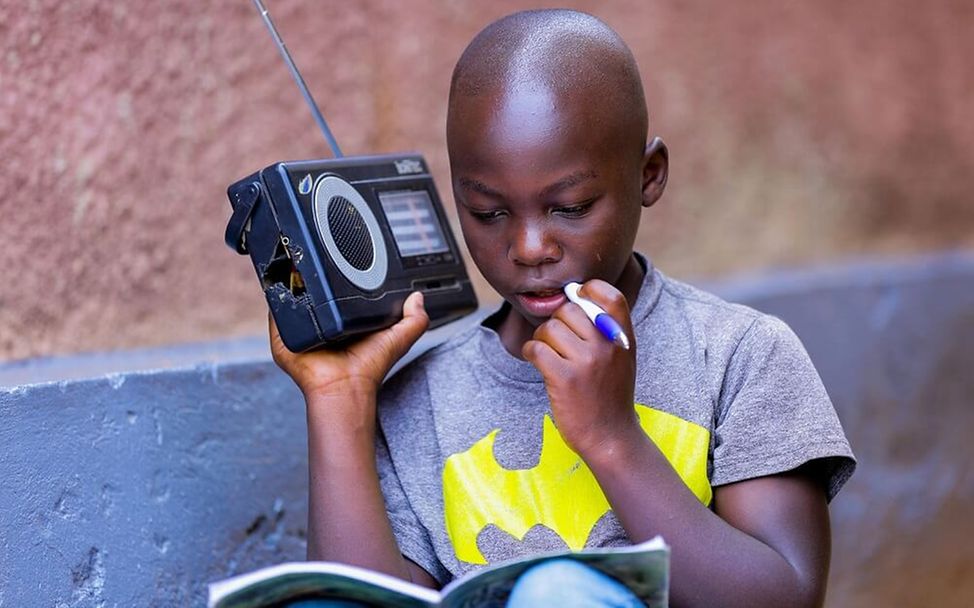 Ruanda: Junge hört sich den Unterricht im Radio an.