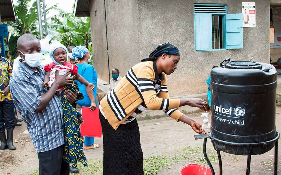 Naturkatastrophen: Spenden für sauberes Wasser  gegen Choleraerkrankung. Eine Familie in Uganda zapft Trinkwasser.