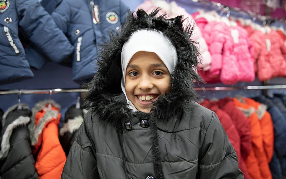 Bargeldhilfe (cash transfer) für warme Winterkleidung: Ein syrisches Mädchen freut sich über ihre Winterjacke. 