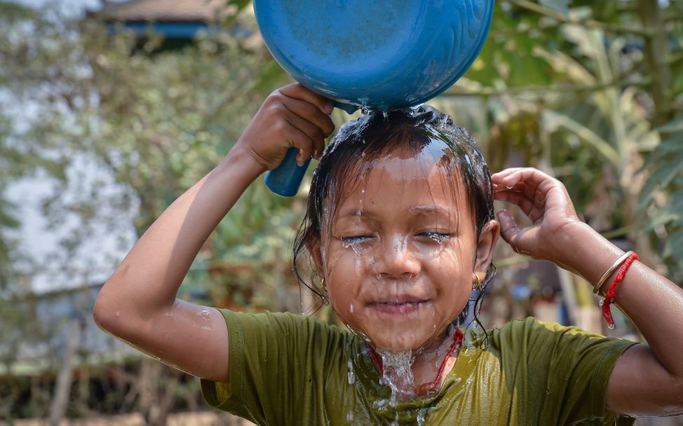 Ein Kind schüttet sich Wasser über den Kopf