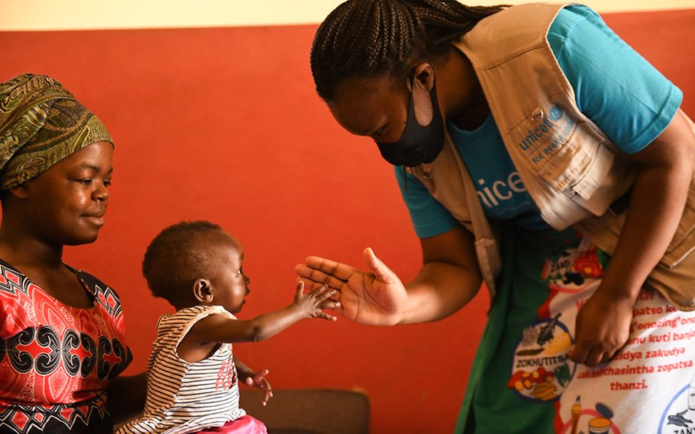 Malawi: Eine UNICEF-Helferin begrüßt ein Kind