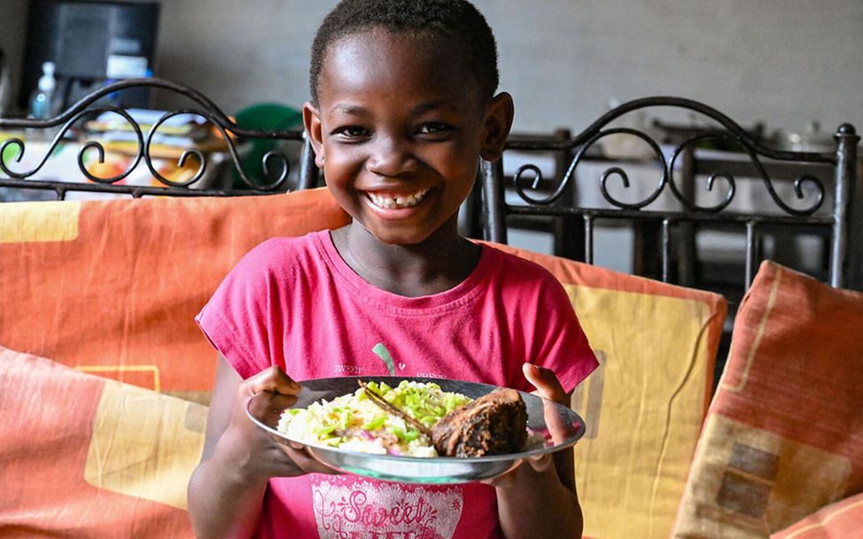 Elfenbeinküste: Ein Mädchen zeigt sein Lieblingsessen: Maniok, Thunfisch, Gemüse