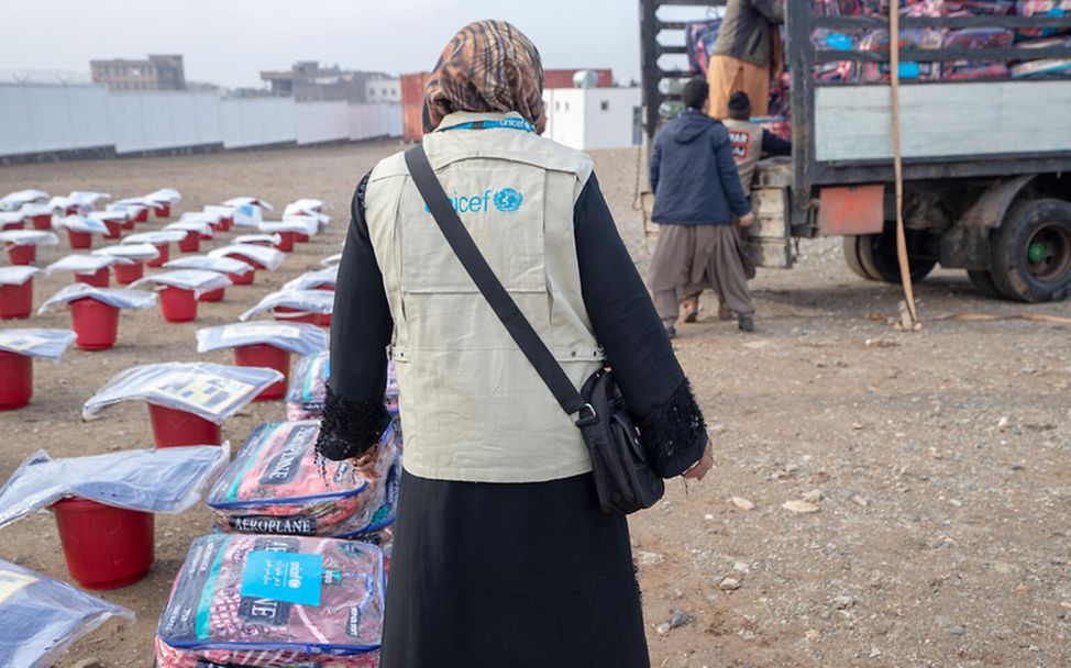 Winter in Afghanistan: Eine UNICEF-Helferin steht neben Decken, die verteilt werden