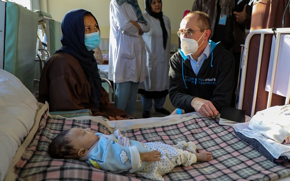 Christian Schneider, UNICEF Deutschland, sitzt neben Mutter und Kind im Krankenhaus in Afghanistan.