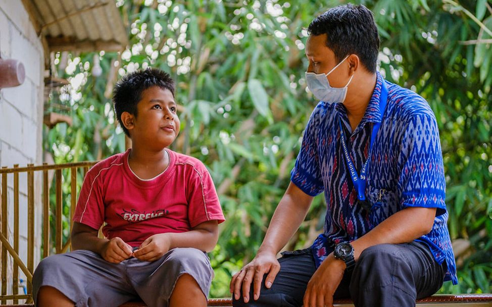 Indonesien: Der 9-jährige Aditia mit einem Sozialarbeiter.