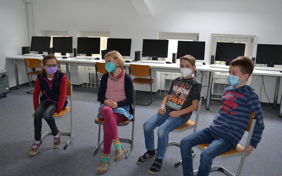 Deutschland: Vier Schüler*innen einer Kinderrechteschule im Sitzkreis.