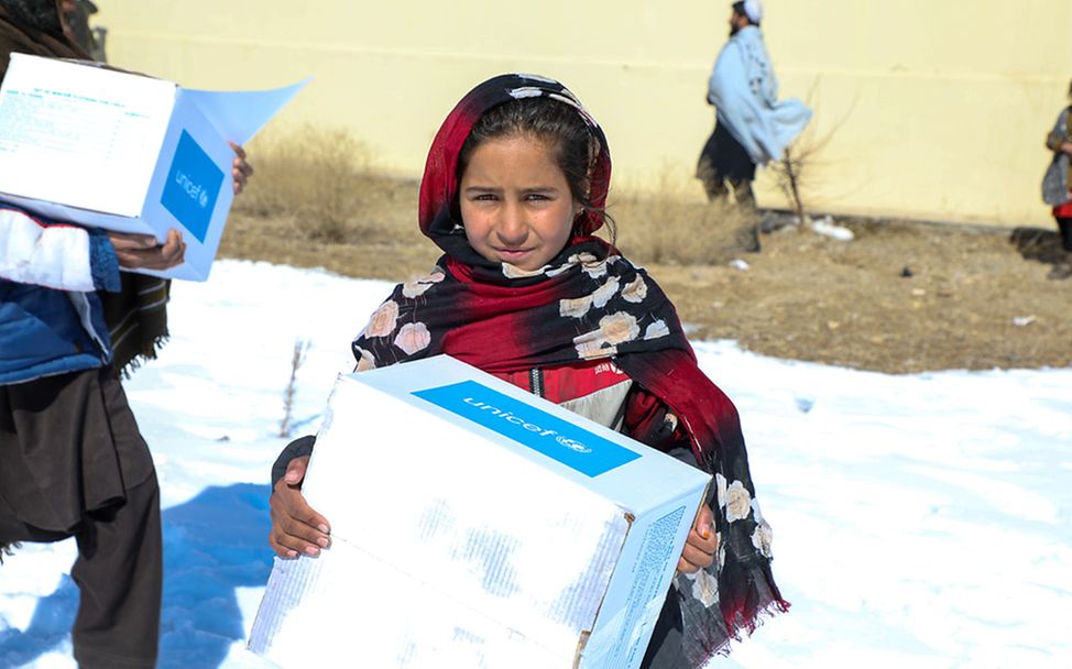 Afghanistan: Ein Mädchen trägt ein Paket mit Winterkleidung