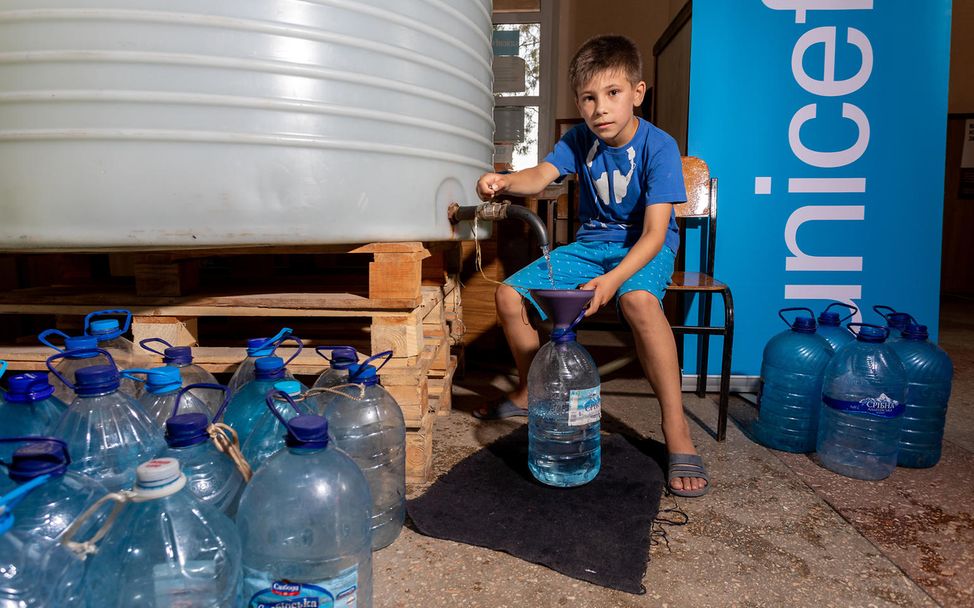 David, acht Jahre alt, hilft beim Abfüllen von 5-Liter-Plastikflaschen.