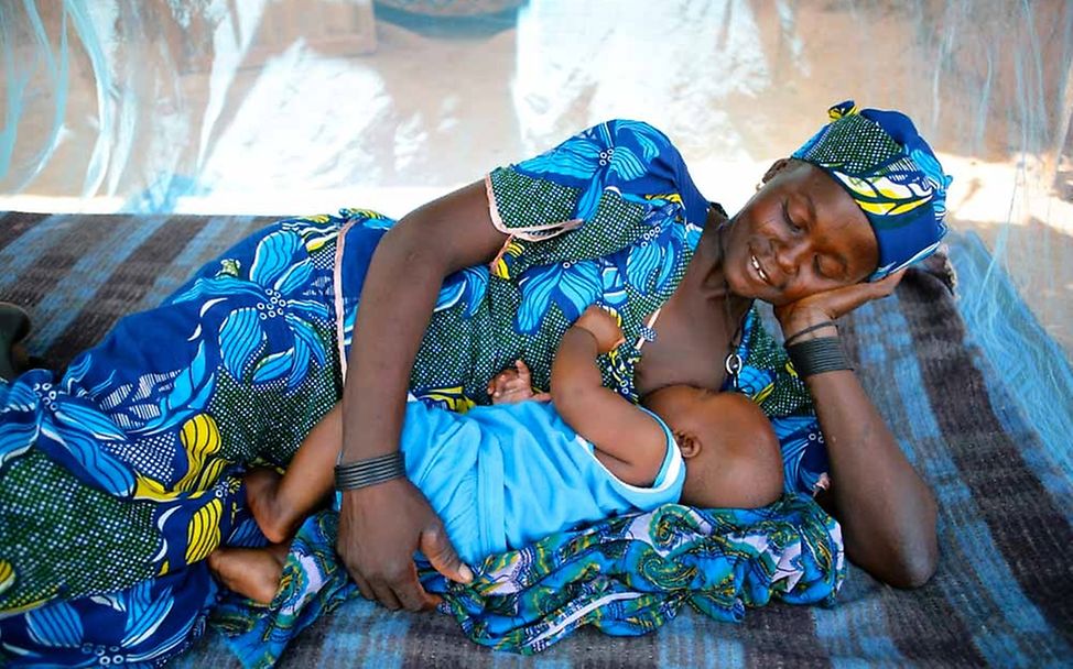 Niger: Eine Mutter stillt ihr Baby unter einem Moskitonetz © UNICEF/Pirozzi