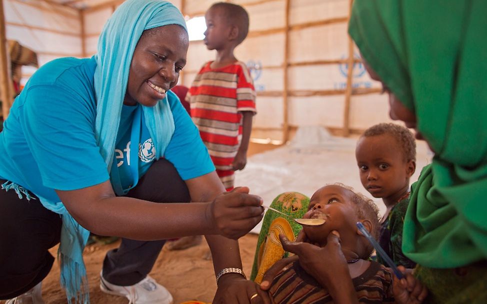 Eine UNICEF-Helferin füttert ein Baby in einem Flüchtlingszelt © UNICEF/NYHQ2012-0579/Jiro Ose