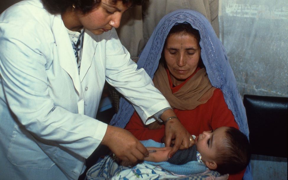 Eine ausgebildete Gesundheitshelferin impft ein Baby © UNICEF/AFGA1992-00044/John Isaac
