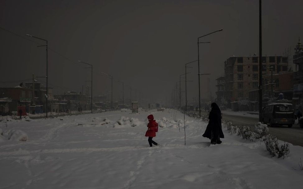 Eine Mutter läuft mit ihrer Tochter durch die verschneiten Straßen von Kabul.