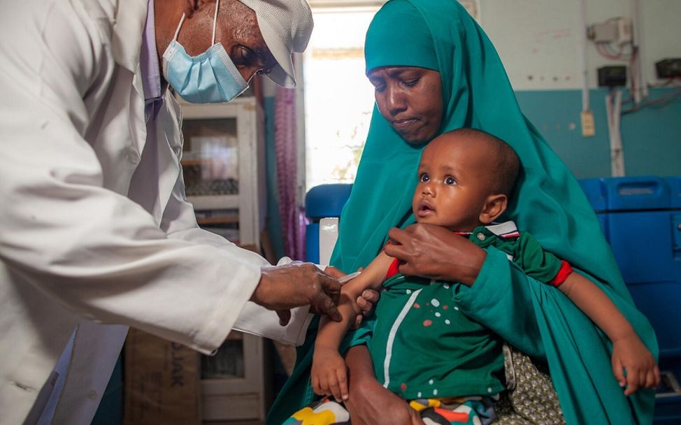 Ein Kind in Somalia wird auf dem Schoß seiner Mutter gegen Masern geimpft.
