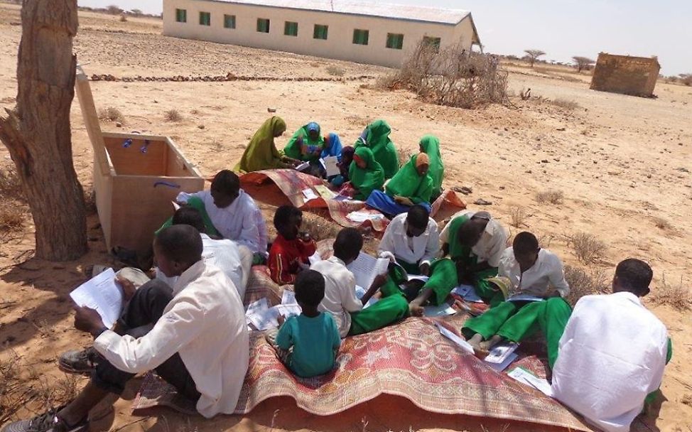 Mädchen und Jungen sitzen beim Lesen getrennt.  © UNICEF Somalia 