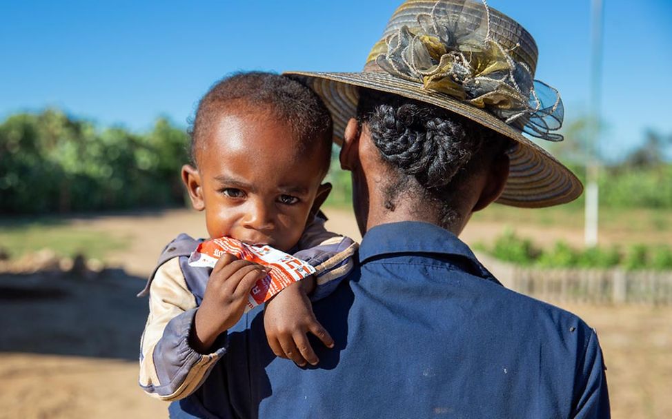 Hunger in der Welt: Ein Junge in Madagaskar isst auf dem Arm seiner Mutter Erdnusspaste.