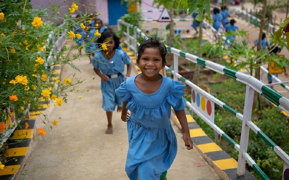 Indien: Mädchen laufen lächelnd einen Weg hinauf