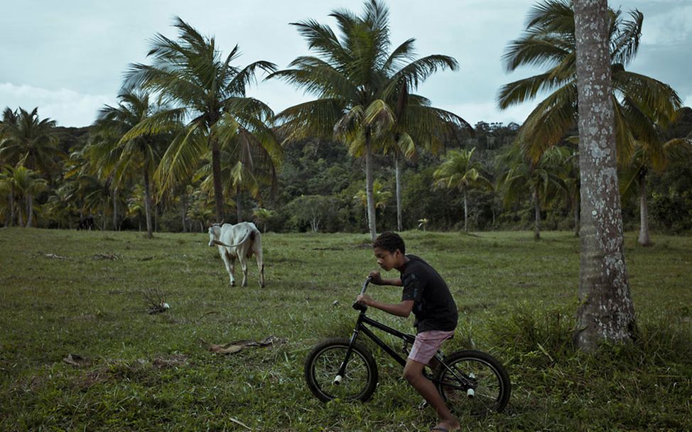 Brasilien: Caio fährt auf seinem Fahrrad über eine Wiese.