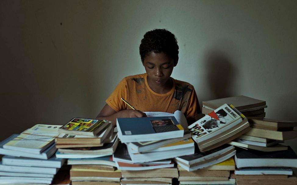 Brasilien: Caio sitzt hinter einem Stapel Bücher und lernt.
