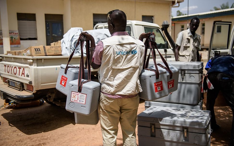 Ein UNICEF-Gesundheitshelfer trägt Kühlcontainer mit Impfstoffen aus.