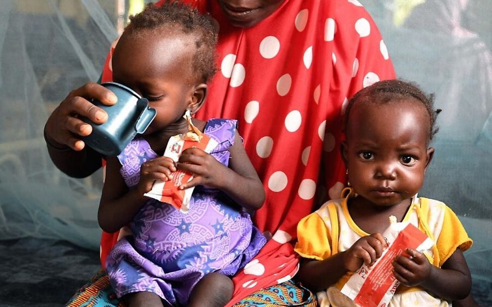 Zwei mangelernährte Kleinkinder werden mit Nahrungsergänzungsmitteln gefüttert.