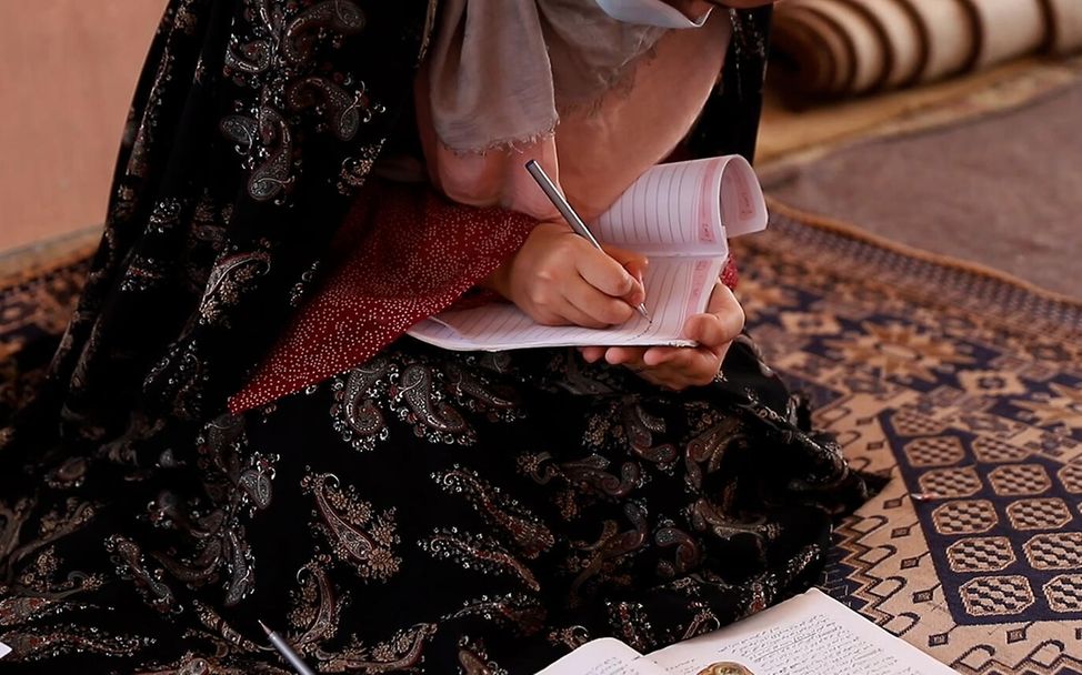 Das Mädchen Mariya aus Afghanistan schreibt in ihr Schulheft.