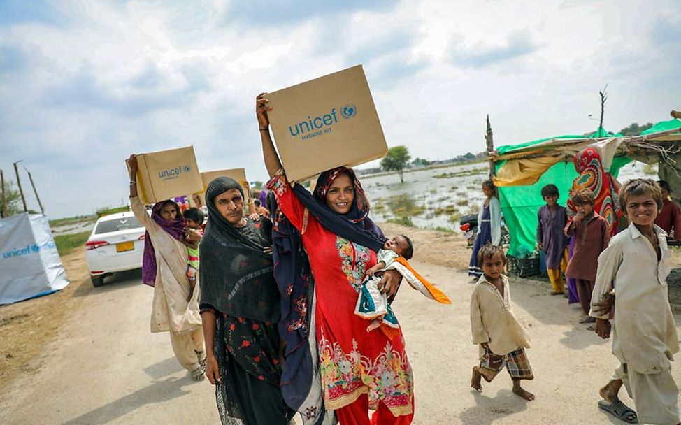 Pakistan: Frauen bringen die von UNICEF erhaltenen Hilfsgüter in ihre provisorischen Unterkünfte. 