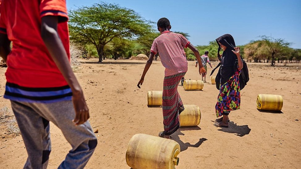 Kenia: Kinder rollen Wasserkanister über den trockenen Boden.