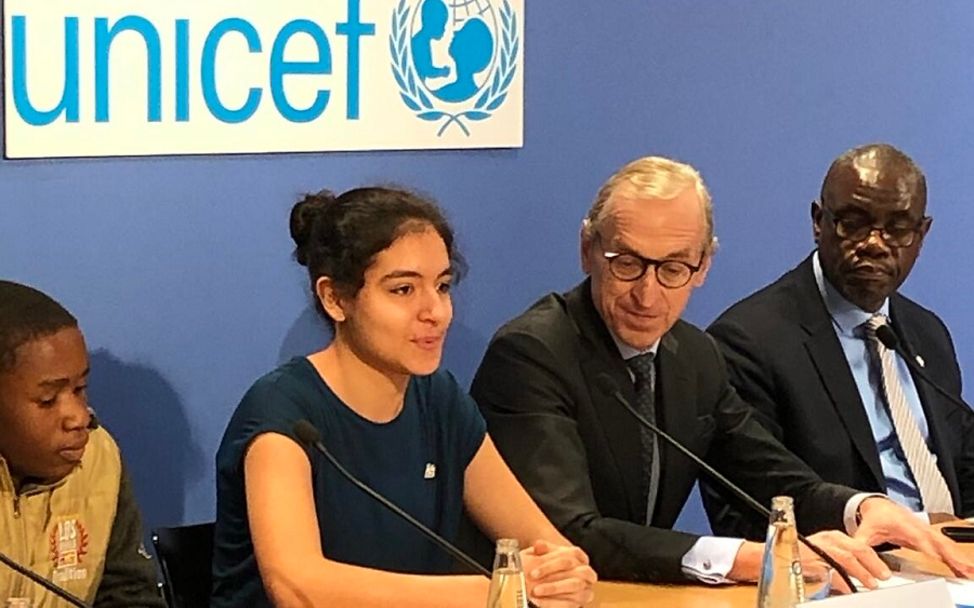 Negin sitzt vor einem UNICEF Logo an einem Pult.