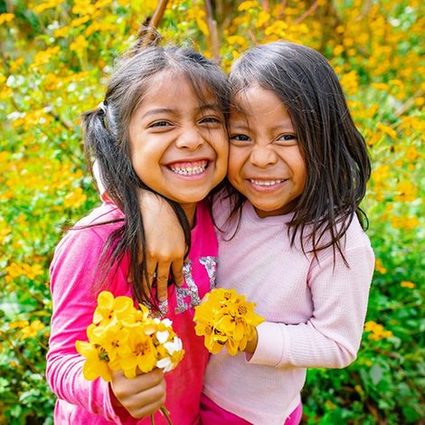Fakten über Mädchen: Zwei lachende Mädchen mit Blumen
