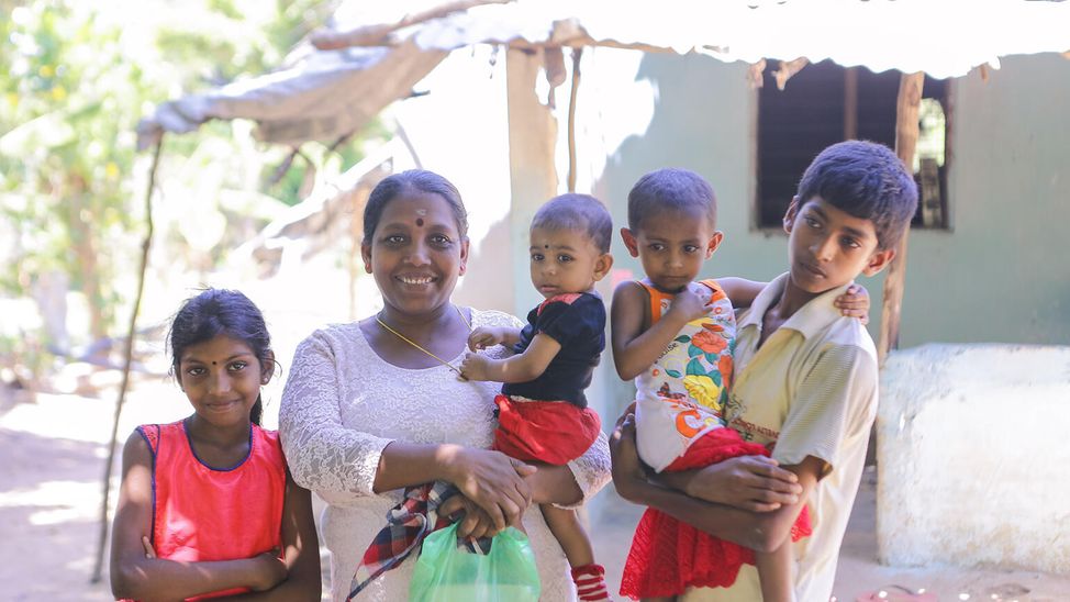 Die gesamte Familie steht vor ihrem Haus in Sri Lanka.