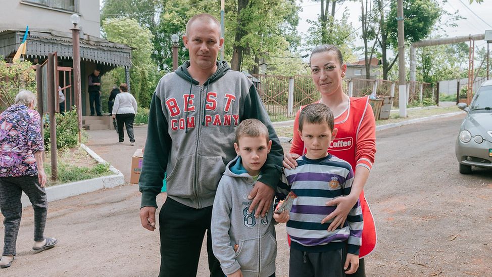UNICEF | Hilfe für Kinder in der Ukraine: Eine Familie mit zwei Kindern steht vor einem Gesundheitszentrum in Charkiw.