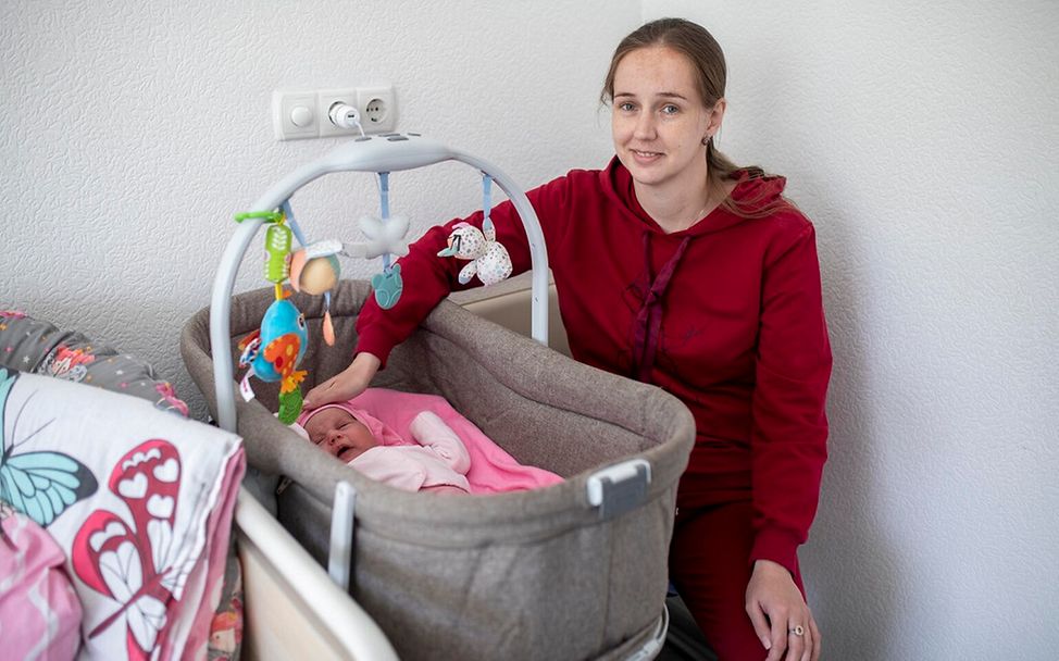 UNICEF | Hilfe für Kinder in der Ukraine: Eine junge sitzt neben ihrem Neugeborenen in einer Babyschale.